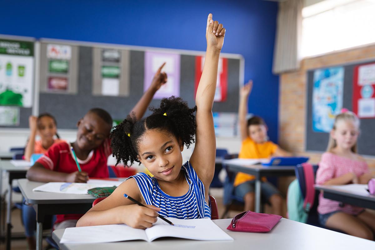 A classroom of students raising their hands