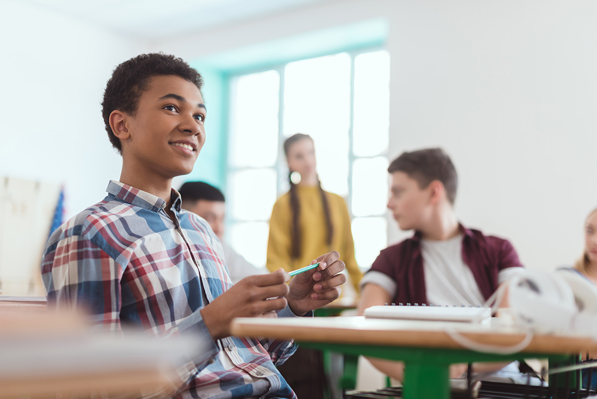 High School student sits at desk playing with a pencil