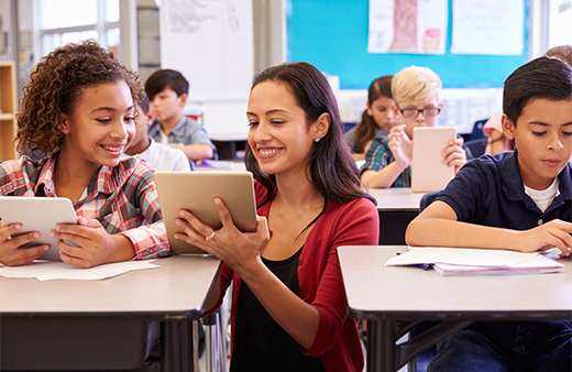 Computer science teacher helps students one-on-one in classroom.