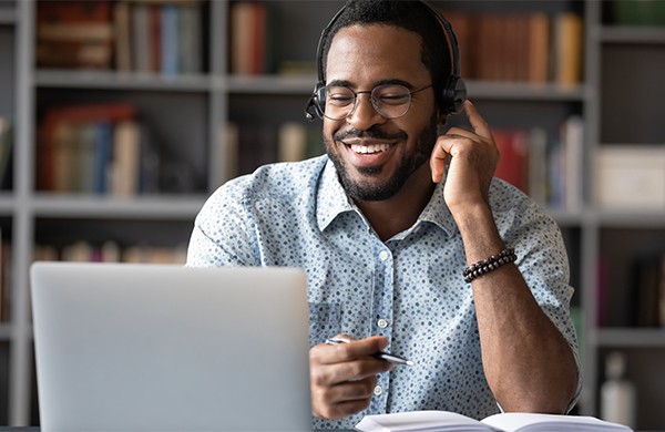 Smiling educator looking at laptop whille wearing headphones