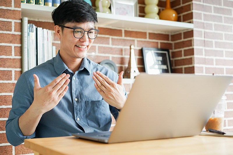 Teacher speaking and gesturing with hands in front of a laptop