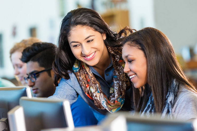 High school student and teacher looking at computer monitor together