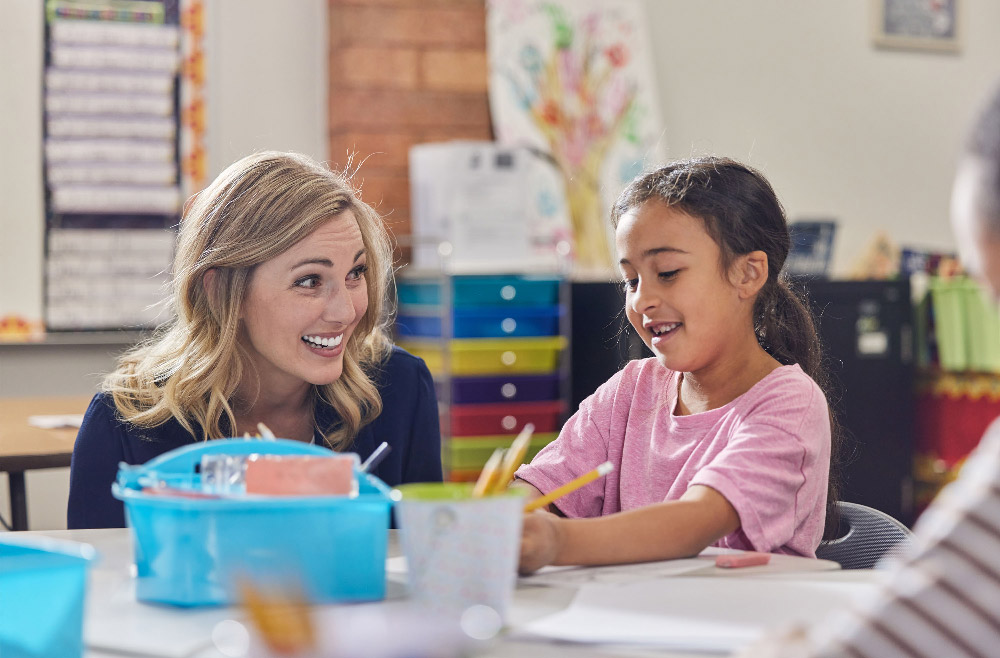 A teacher interacting with students at a table in a classroom