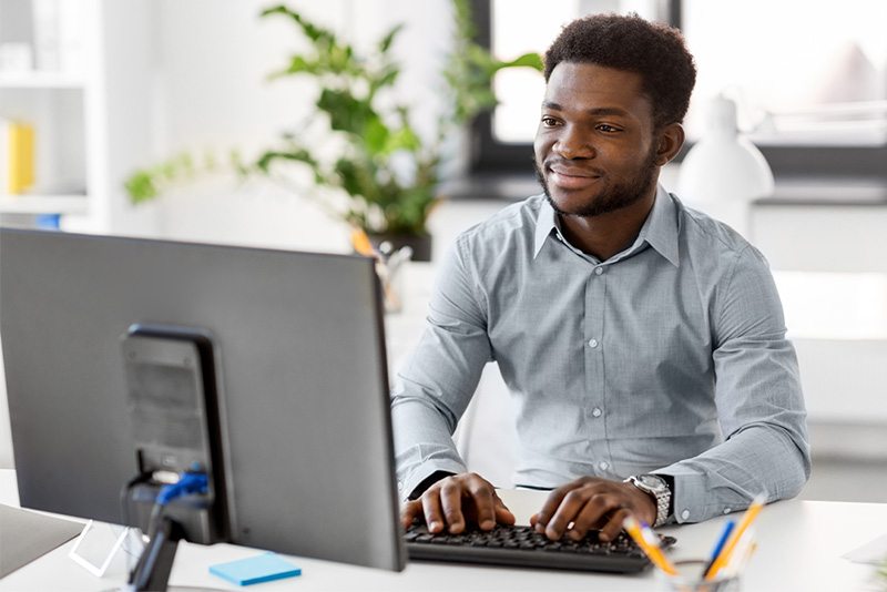 Educator sitting at desk and typing on keyboard.