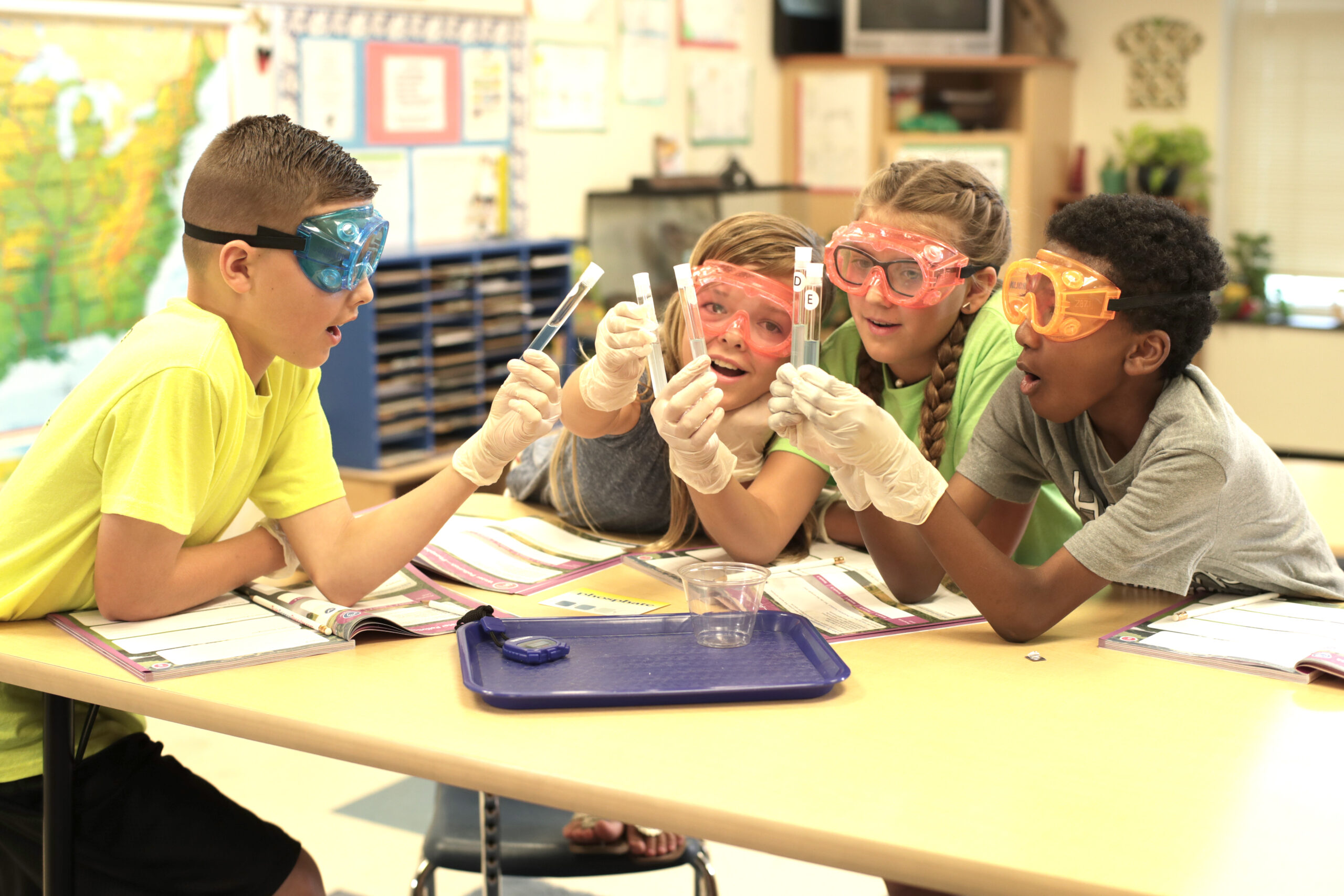 A group of students wearing safety gloves and goggles conducting a science experiment in the classroom