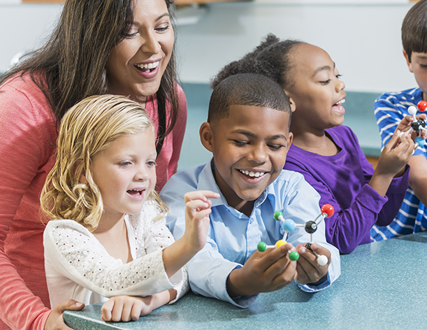 A pair of pre-k students holding and manipulating a molecular model