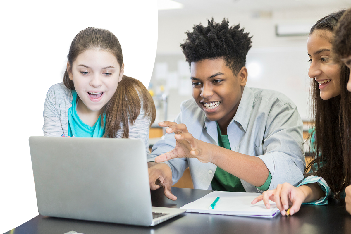 Group of middle school students gathered around a laptop while smiling and looking at the screen