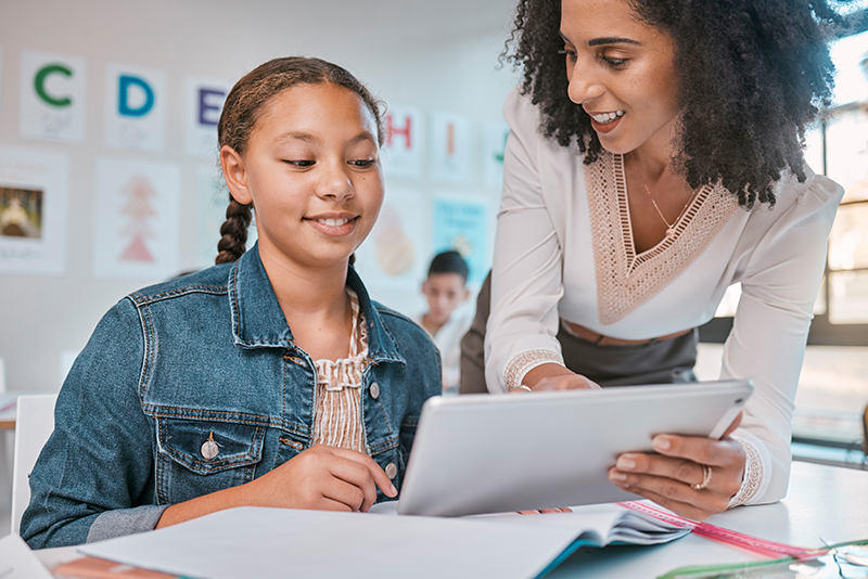 Elementary school student and teacher looking at a tablet together